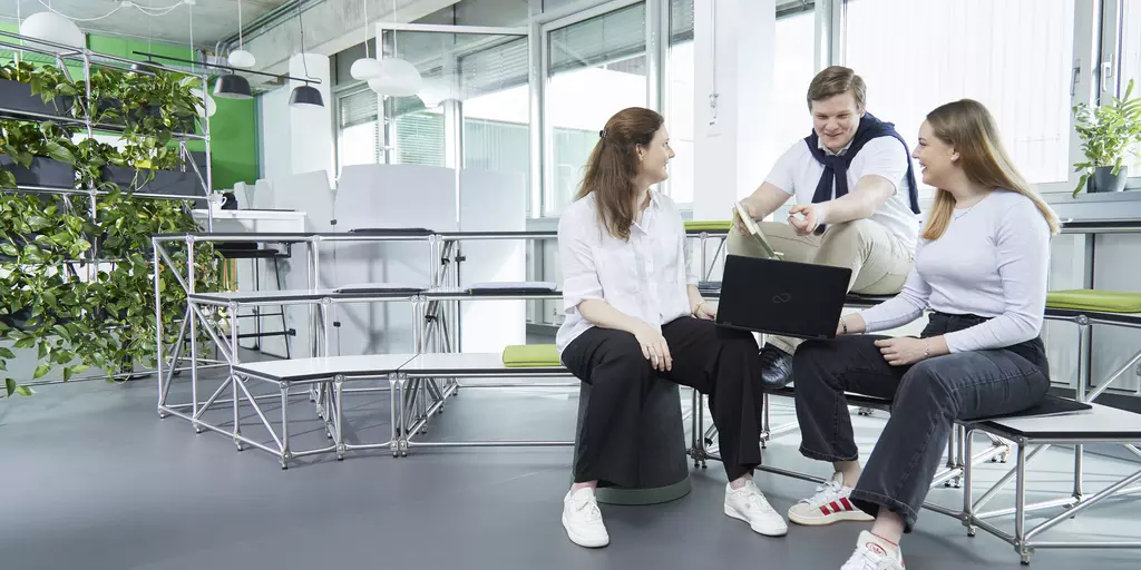 Drei Mitarbeitende der Schwabe-Gruppe sitzen im Atrium.