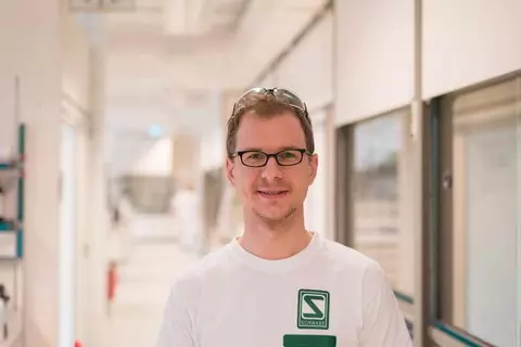 Lächelnder Mitarbeiter mit Schutzbrille