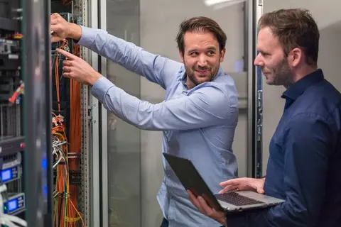 Zwei Männer mit Laptop vor Serverschrank