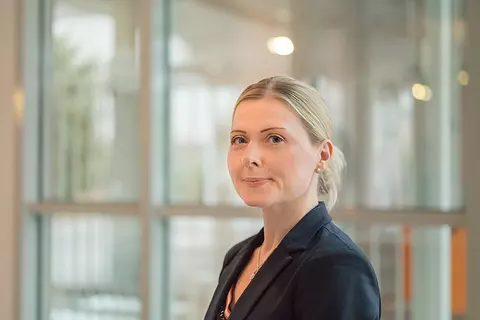 Mitarbeiterin in Blazer im Eingangsbereich der Bürogebäude