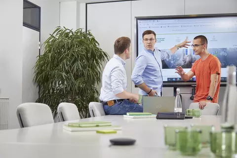 Drei Personen im Austausch in einem Besprechungsraum