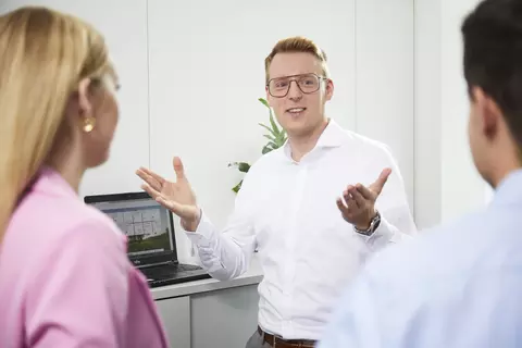 Ein Mann unterhält sich mit zwei Personen.